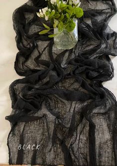 a vase filled with flowers sitting on top of a piece of black organe fabric