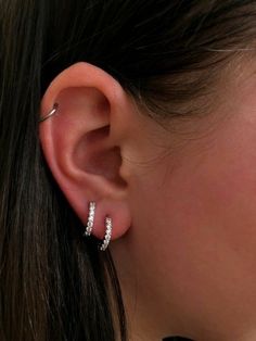 a close up of a person's ear with two diamond hoops on it