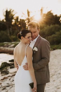 a bride and groom embracing on the beach