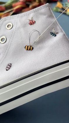 a pair of white shoes with bee charms hanging from the shoelaces on a string