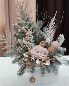 a vase filled with flowers and greenery on top of a table