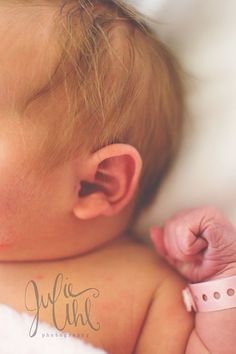 a close up of a baby laying on top of a white blanket with its head turned to the side