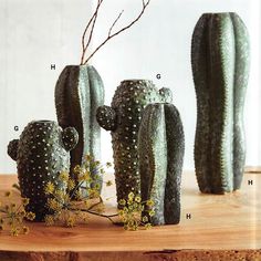 three cactus shaped vases sitting on top of a wooden table