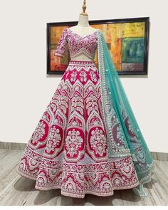 a pink and green lehenga on display in front of a painting