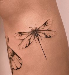 a woman's thigh with a dragonfly tattoo on the side and an insect sitting on top of it