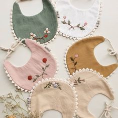 four bibs with flowers on them are laid out in the shape of baby bibs