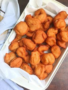 some fried food is in a white container on a table next to a napkin and fork