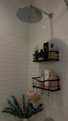 a bathroom with white tiles and black shelves on the wall, along with a shower head