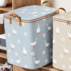 two blue and white storage bags with geese on them, one is holding a book