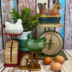 an assortment of old fashioned clocks and other items on a wooden table next to a plant