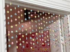 some little stars hanging from the ceiling in front of a window with pink and blue curtains