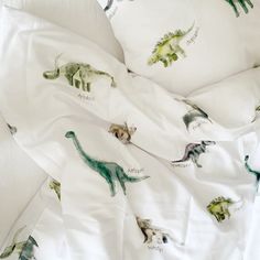 an unmade bed with dinosaur sheets and pillows