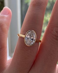 a woman's hand with a ring on it that has an oval shaped diamond in the center