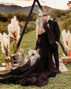 a bride and groom kissing in front of an altar with tall pamodia flowers