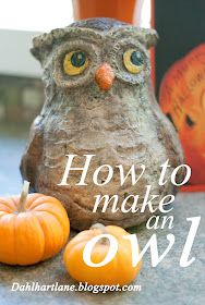 an owl statue sitting next to two small pumpkins