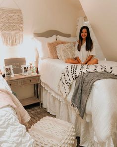 a woman sitting on top of a white bed in a bedroom next to a dresser