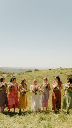 a group of bridesmaids standing in a field with their bouquets and flowers