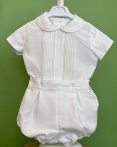 An elegant two-piece set for baby boys to wear during any special occasion. The top has a peter pan collar, geometrical frontal lace, handmade pleats, and short sleeves; it has buttons on the back for closure. The bottom is bubble shorts with buttons on the sides for closure and an elastic band on the back. The interior, or lining, is made with cotton fabric, while the exterior is white organza. Dry clean 2 piece set Interior: 100% cotton; exterior: 100% polyester Made in Spain Final Sale Baptism Outfits For Boys, Spain Shirt, Toddler Baptism, Bubble Outfit, Heirloom Portraits, Bubble Clothes, Catholic Baptism, Bubble Shorts, Boy Baptism Outfit