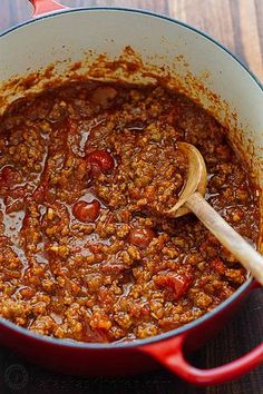 a red pot filled with chili on top of a wooden table