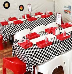 the tables are covered with black and white checkered tablecloths, red place mats, and plastic chairs