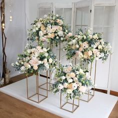 three gold vases with white flowers and greenery