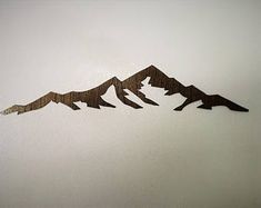 three mountains cut out of wood sitting on top of a white wall