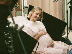 a pregnant woman sitting in a hospital bed