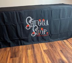 a black table cloth with the words sugga shop on it sitting in front of a wooden floor