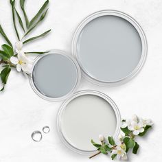 three white paint cans with flowers and two wedding rings on the table top view from above