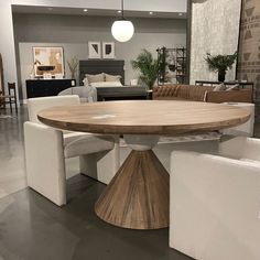 a round wooden table surrounded by white chairs