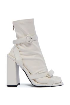 The AZALEA WANG Quinlan White Sandal Bootie is a unique hybrid style featuring a stretchy, removable faux leather sock with an ankle-high shaft, tonal stitching, and a tonal inner ankle zipper closure. The coordinating faux leather sandal features a chunky block heel, an almond toe silhouette, dual bow-adorned toe bands, and a textured rubber outsole. Complete with a wrap-around ankle strap and circular buckle detailing.  (all measurements are approximate from size 7.5) - Faux Leather Upper - Almond Toe - Chunky Heel - Ankle-High Shaft - 4.5” Heel Height - 12.5” Sock Shaft Length - Imported  Product ID: 428685 Sock Bootie, White Sandal, Azalea Wang, Leather Socks, Chunky Block Heels, White Sandals, White Sock, Chunky Heel, Fast Fashion