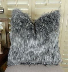 two gray furry pillows sitting on top of a chair