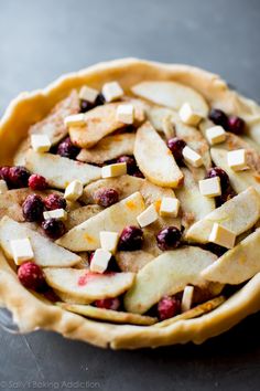 an apple pie with cranberries and cheese on top