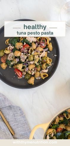 healthy tuna pesto pasta with spinach and tomatoes in a skillet on a marble countertop