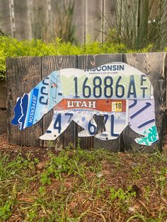 a wooden sign with the shape of a bear on it's side in front of some grass