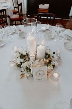 a white table topped with lots of candles and flower centerpieces on top of it