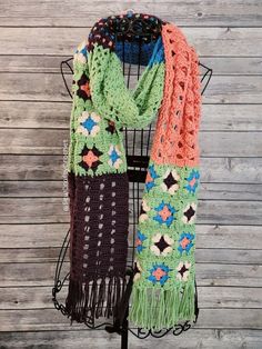 a multicolored crocheted scarf hanging on a rack