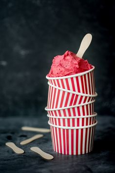 a red and white striped paper cup with spoons in it on a black surface