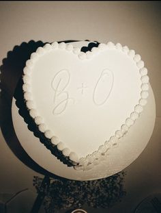 a white heart shaped cake with the initials b and o on it's side