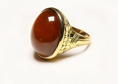 Gold Cabochon Carnelian Men's Ring. This antique yellow gold cabochon carnelian men's ring features a intricate floral motif design, showcasing a stunning cabochon carnelian gemstone. Ring is currently size 9.5 and it can be resized upon request. Carnelian Yellow Gold Rings With Oval Cabochon, Elegant Carnelian Oval Cabochon Ring, Carnelian Cabochon Ring Gift, Luxury Men's Carnelian Gemstone Ring, Floral Motif Design, Luxury Men's Carnelian Cabochon Ring, Montblanc Pen, Costume Jewelry Earrings, Motif Design