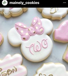 decorated cookies with pink and white icing are arranged on a table top, including minnie mouse