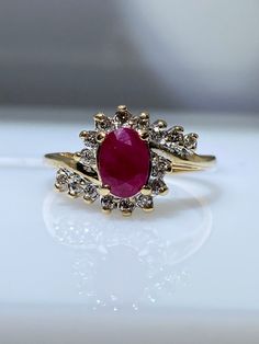 10K yellow gold ring with genuine ruby and diamonds. This oval shaped ruby weighs 0.50 carats and has a deep red hue. It is surrounded by a diamond halo that trickles down the shank. The total diamond weight is 0.16 carats. Finger size is 6.5 Resizing, if needed, comes complimentary. Feel free to message me if you have any other questions. Oval Ruby Cluster Ring With Diamond Accents, Oval Diamond Ring With Lab-created Ruby Accents, Red Oval Diamond Ring With Accents, Oval Red Diamond Ring With Accents, Gold Oval Ruby Halo Ring, Oval Ruby Halo Ring In Gold, Opal Ring Vintage, Ruby And Diamond Ring, Afghan Clothes