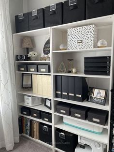 a white bookcase filled with lots of black and white boxes on top of it