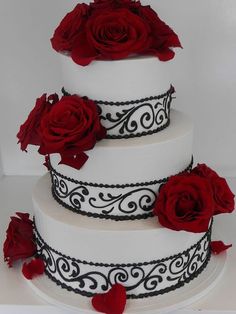 a three tiered white cake with red roses on the side and black trimmings