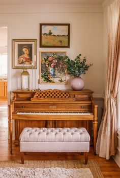 there is a piano in the living room with pictures on the wall and a bench next to it