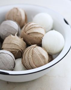 a white bowl filled with lots of different types of yarn balls on top of a table