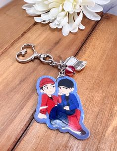 a keychain with an image of two people sitting next to each other on top of a wooden table