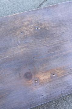 a wooden bench with nails on it sitting on the concrete floor next to a sidewalk