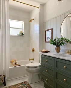 a white bathroom with green cabinets and a toilet next to a bathtub in the corner