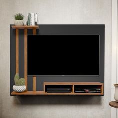 a flat screen tv mounted to the side of a wooden shelf next to a potted plant